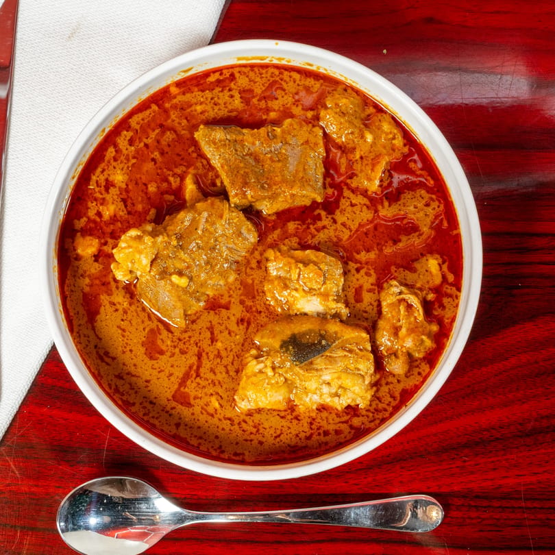 El Afrik Cuisine and Bar's African stew with meat in a white bowl on a red table.