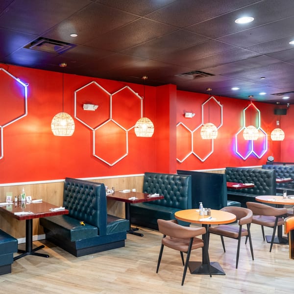El Afrik Cuisine and Bar's dining room with red walls, blue booths, and geometric neon lights.