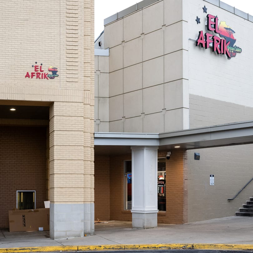 Exterior view of El Afrik Cuisine and Bar, with its logo on a light brick building.