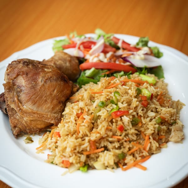 Crispy fried chicken, vegetable fried rice, and a fresh garden salad on a white plate.