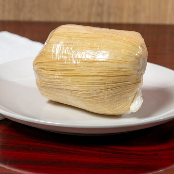 A wrapped African dish, possibly fufu or kenkey, on a white plate at El Afrik Cuisine and Bar.