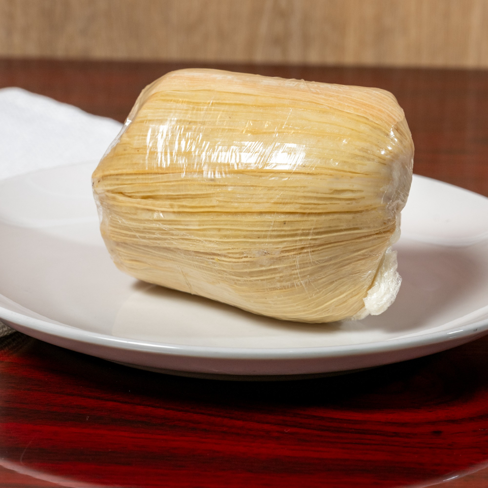 A wrapped African dish, possibly fufu or kenkey, on a white plate at El Afrik Cuisine and Bar.